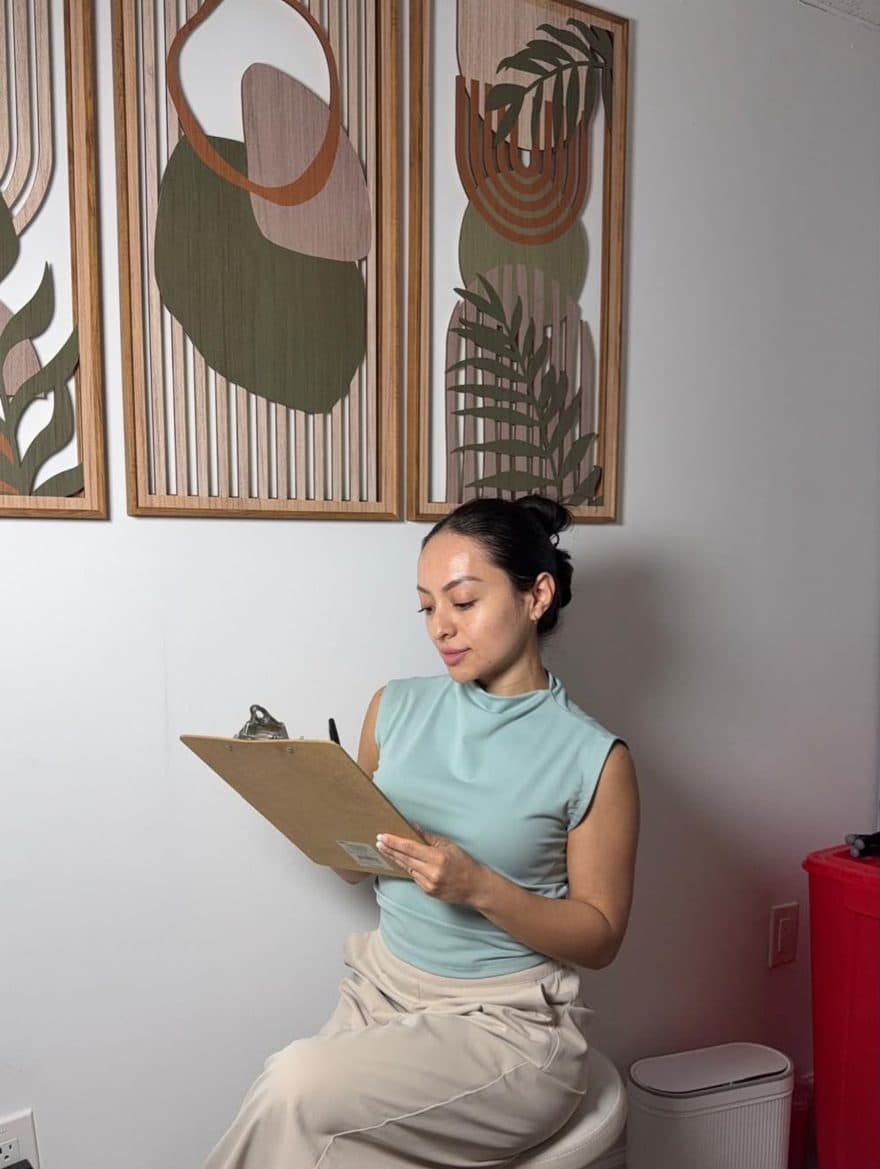 Issa Espinoza at Skin by Issa, reviewing a client chart on a clipboard